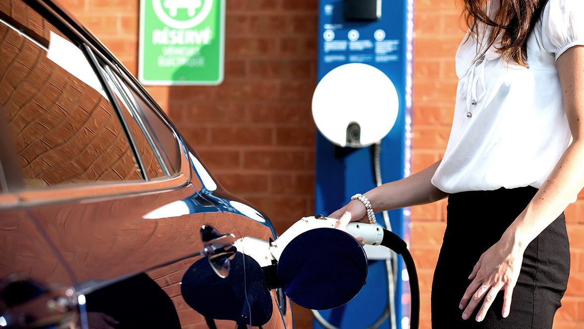 woman charging her car at a charging point woman charging her car at a charging point